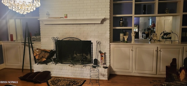 living room with a brick fireplace, dark hardwood / wood-style floors, and an inviting chandelier