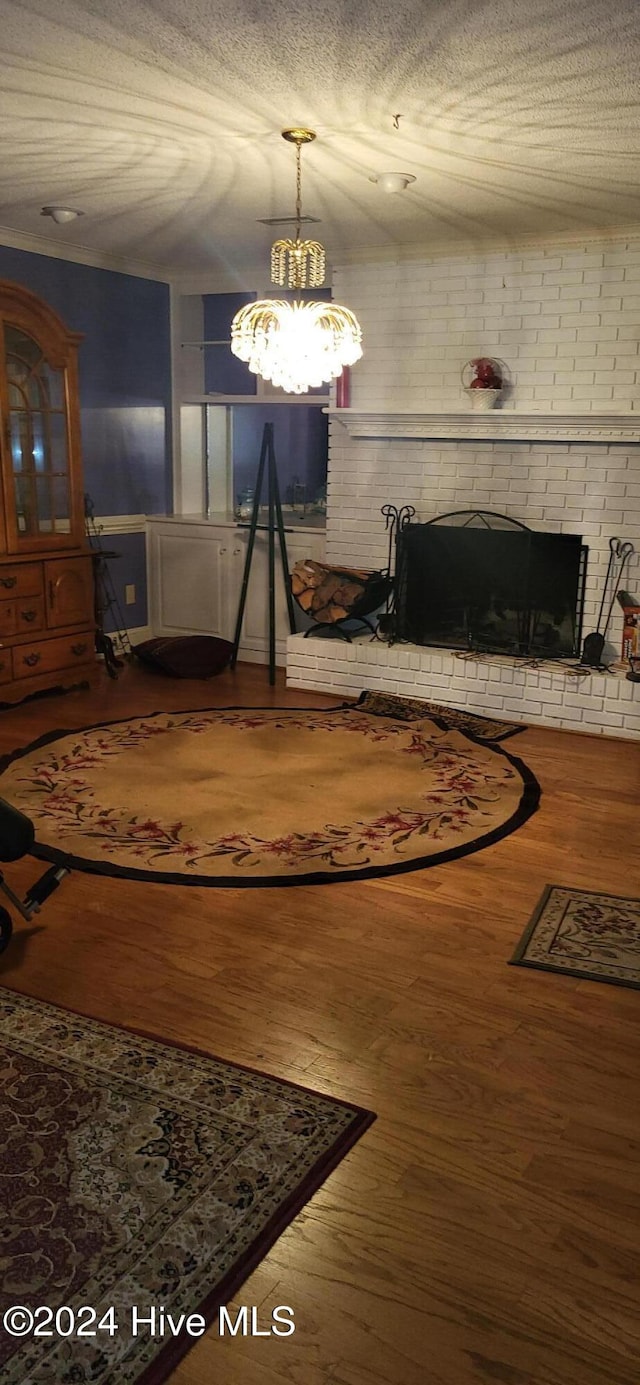 interior space with a brick fireplace, a textured ceiling, and wood finished floors