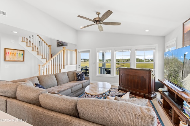 living area featuring plenty of natural light, stairs, vaulted ceiling, and wood finished floors