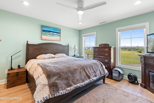 bedroom featuring recessed lighting, a fireplace, wood finished floors, visible vents, and baseboards