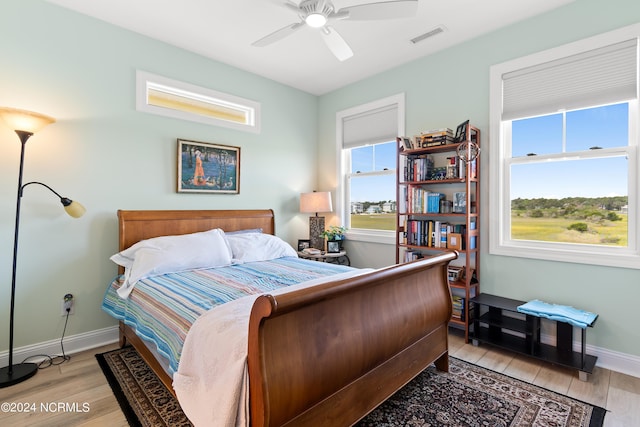 bedroom featuring a ceiling fan, visible vents, light wood-style flooring, and baseboards