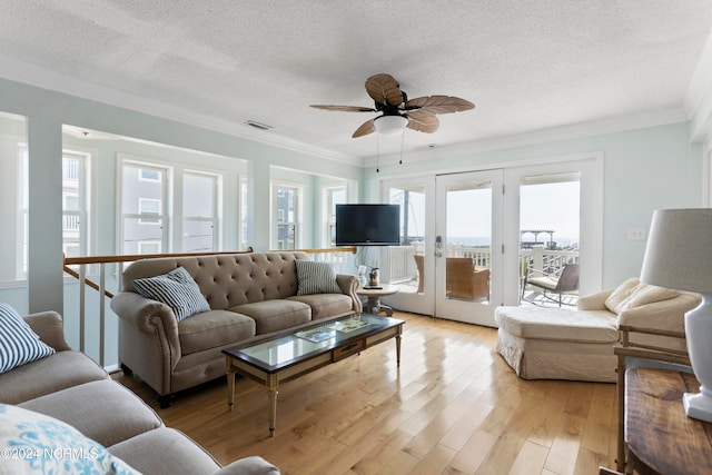 living room featuring light wood-type flooring, ceiling fan, crown molding, and french doors