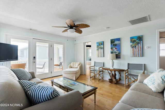 living room featuring a textured ceiling, light hardwood / wood-style flooring, french doors, crown molding, and ceiling fan