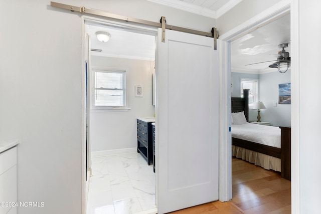 corridor featuring a barn door, ornamental molding, and light hardwood / wood-style flooring