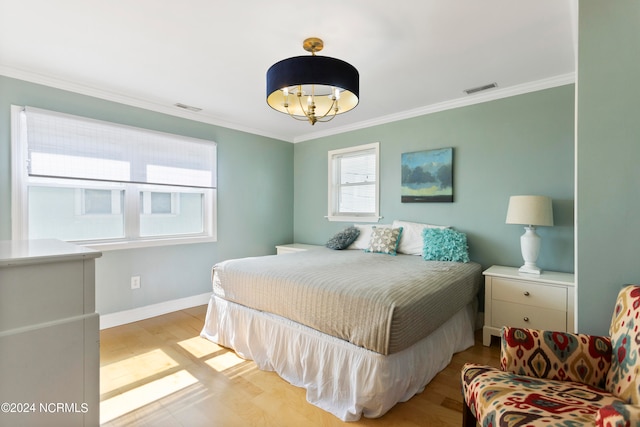 bedroom with an inviting chandelier, crown molding, and light hardwood / wood-style flooring