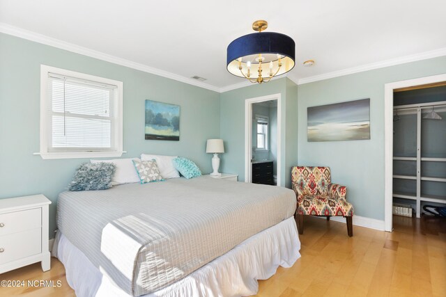 bedroom featuring ornamental molding, multiple windows, light hardwood / wood-style flooring, and a closet