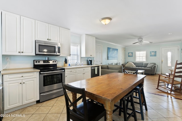 kitchen featuring crown molding, white cabinetry, light tile patterned floors, ceiling fan, and appliances with stainless steel finishes