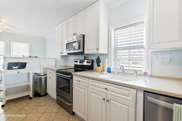 kitchen featuring ornamental molding, light tile patterned floors, stainless steel appliances, sink, and white cabinets