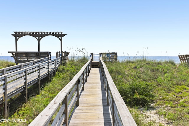 view of dock with a pergola and a water view