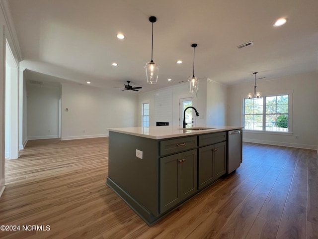 kitchen with a kitchen island with sink, stainless steel dishwasher, wood-type flooring, ceiling fan with notable chandelier, and sink