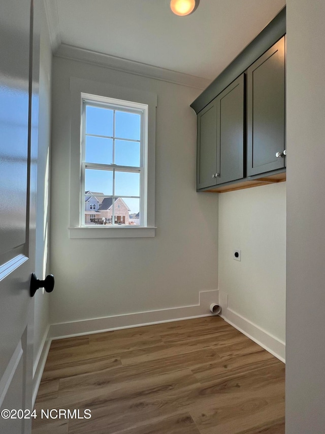 laundry room with cabinets, crown molding, hardwood / wood-style flooring, and electric dryer hookup