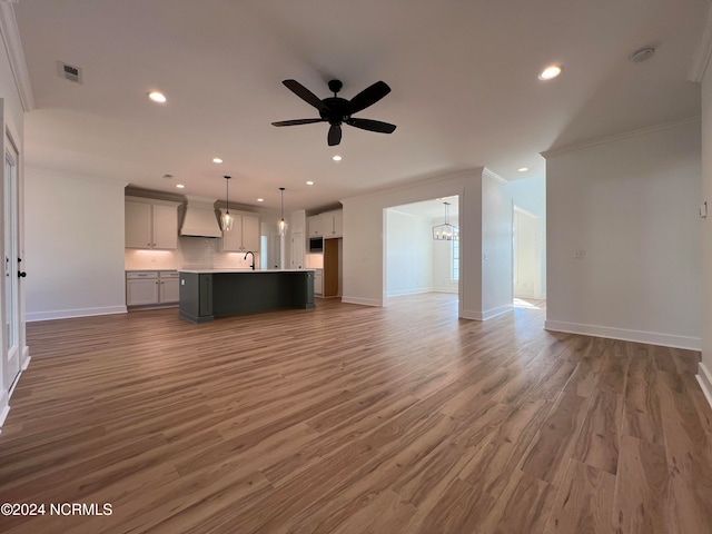 unfurnished living room featuring ornamental molding, sink, dark hardwood / wood-style floors, and ceiling fan