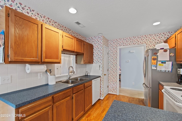 kitchen featuring white appliances, dark countertops, a sink, and visible vents