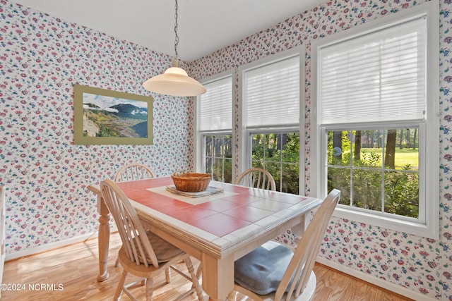 dining room featuring baseboards, light wood-style flooring, and wallpapered walls