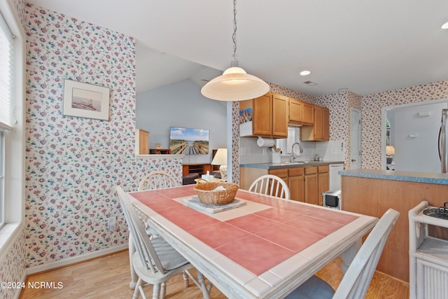 dining area featuring wallpapered walls, baseboards, vaulted ceiling, and light wood-style floors