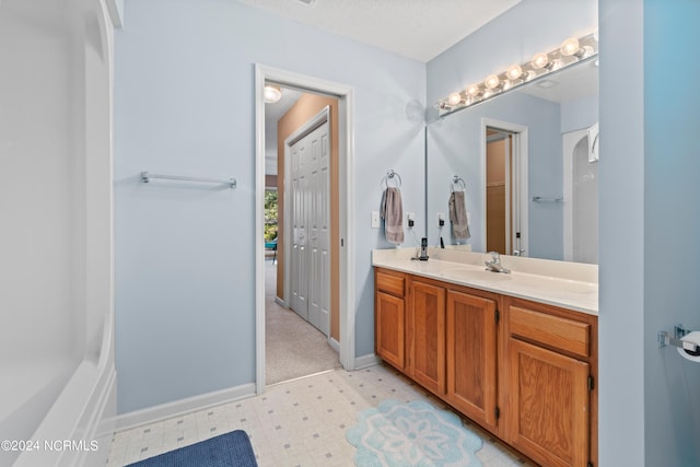 bathroom with a closet, a textured ceiling, vanity, baseboards, and tile patterned floors