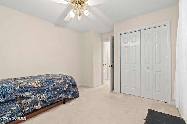 bedroom with a ceiling fan, a closet, light carpet, and baseboards