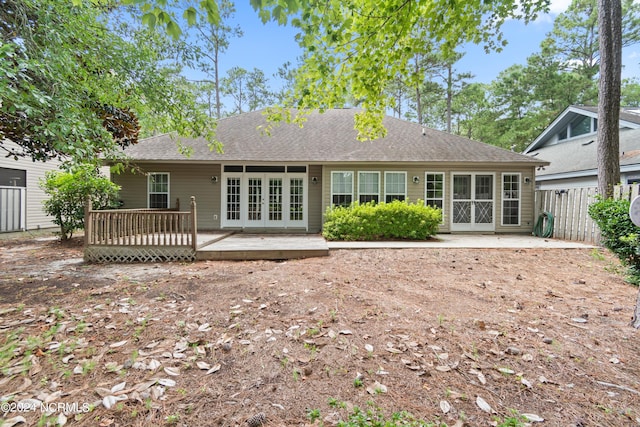 back of house featuring a wooden deck, fence, roof with shingles, and french doors