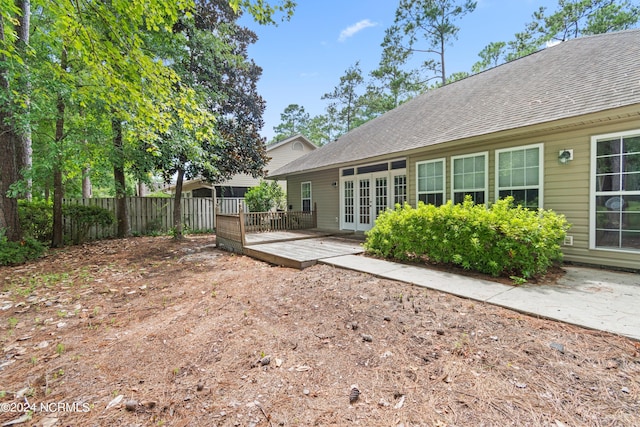 rear view of property with french doors, roof with shingles, and fence