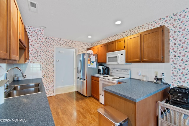 kitchen featuring white appliances, wallpapered walls, visible vents, dark countertops, and a sink