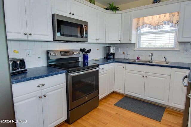 kitchen with light wood-type flooring, stainless steel appliances, decorative backsplash, and white cabinetry