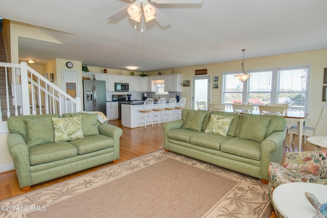 living room with light wood-type flooring and ceiling fan