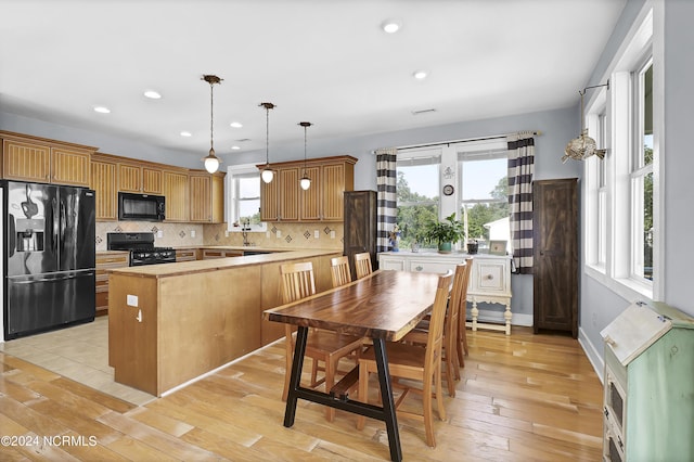 kitchen featuring black appliances, a healthy amount of sunlight, and hanging light fixtures