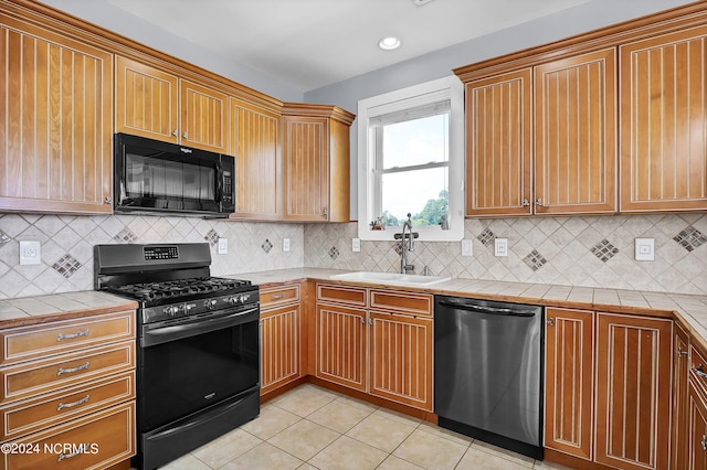 kitchen with range with gas cooktop, stainless steel dishwasher, sink, tile counters, and light tile patterned floors