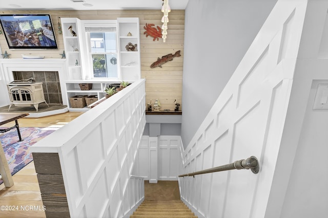 stairway with hardwood / wood-style flooring, a wood stove, and wooden walls