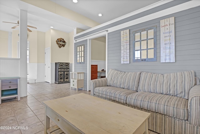 living room featuring ceiling fan, tile patterned flooring, and wood walls