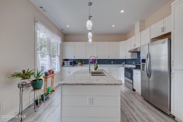 kitchen featuring white cabinets, stainless steel appliances, sink, backsplash, and a kitchen island with sink