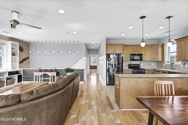 kitchen with decorative light fixtures, ceiling fan, backsplash, black appliances, and light wood-type flooring