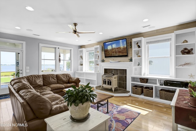 living room featuring ceiling fan, a wood stove, and light wood-type flooring