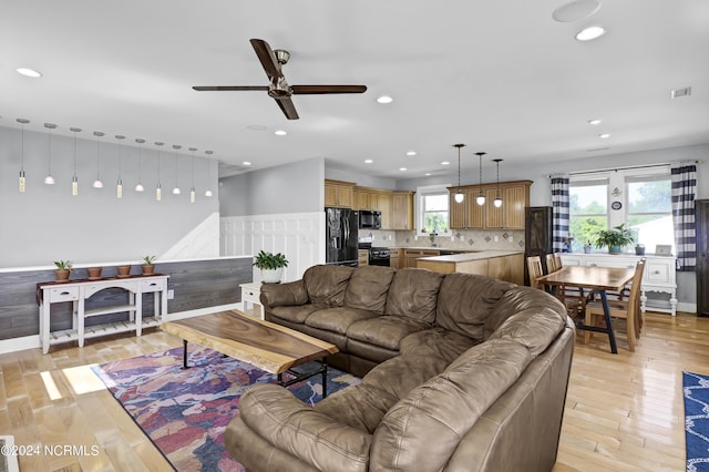 living room with light hardwood / wood-style floors, plenty of natural light, and ceiling fan