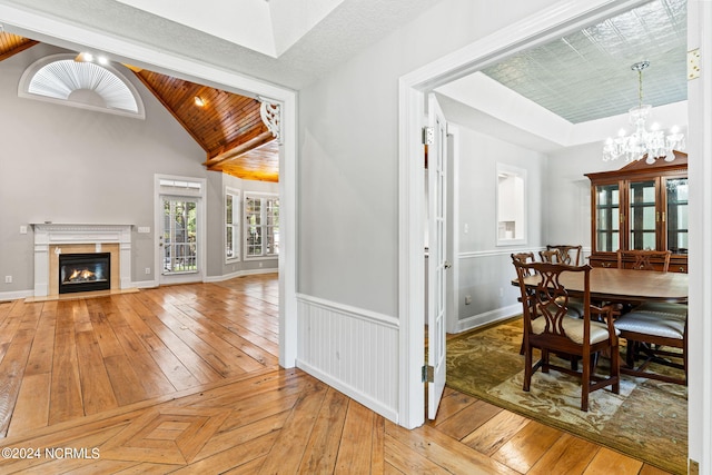 dining area with light parquet floors, a high end fireplace, wooden ceiling, a chandelier, and lofted ceiling