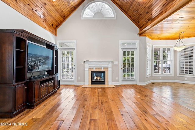 unfurnished living room with a wealth of natural light, light wood-style floors, wood ceiling, and a high end fireplace