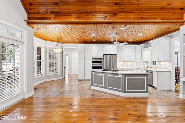 kitchen with a kitchen island, tasteful backsplash, white cabinetry, appliances with stainless steel finishes, and wood ceiling