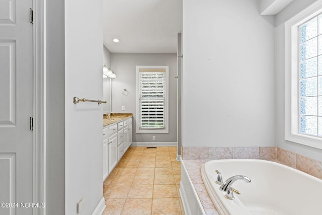 bathroom featuring tile patterned flooring, plenty of natural light, a relaxing tiled tub, and vanity