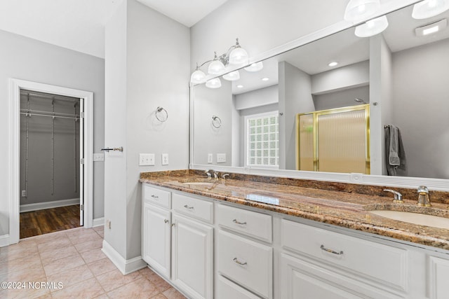 bathroom featuring tile patterned floors, double vanity, a shower stall, and a sink