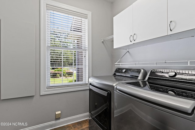 clothes washing area featuring cabinet space, dark tile patterned flooring, baseboards, and separate washer and dryer