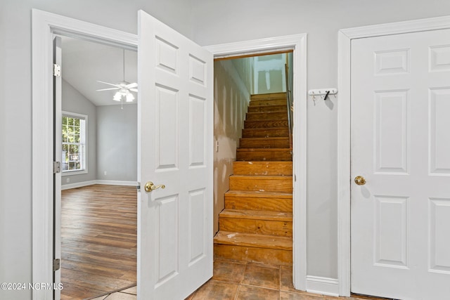 stairs featuring baseboards, lofted ceiling, a ceiling fan, and wood finished floors