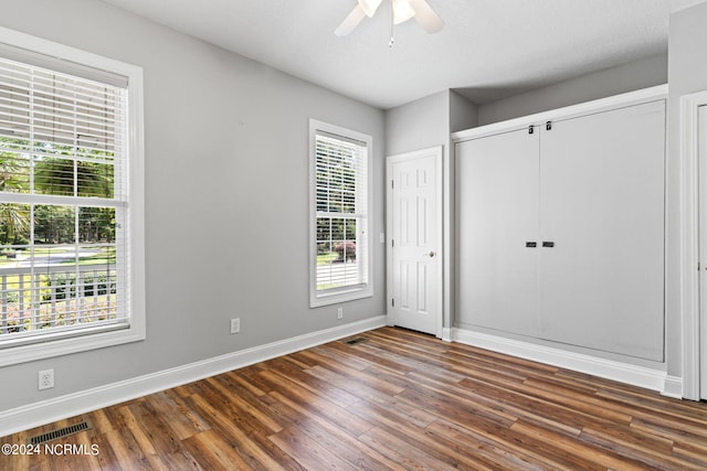 unfurnished bedroom featuring visible vents, multiple windows, and wood finished floors