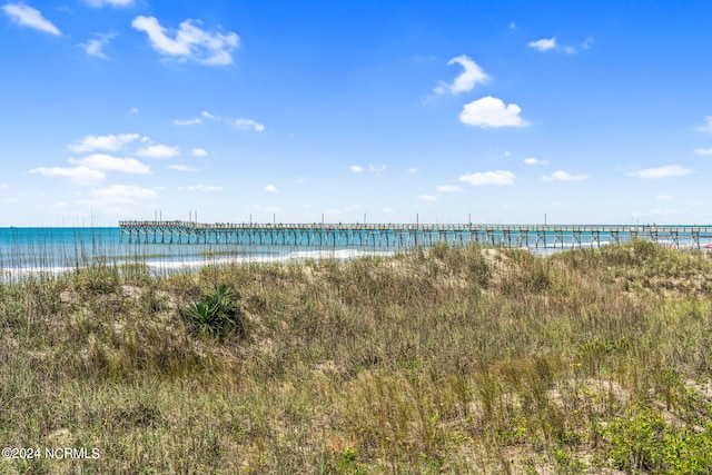 property view of water featuring a pier and a beach view