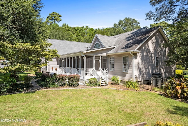 rear view of house featuring a yard, a sunroom, and roof with shingles