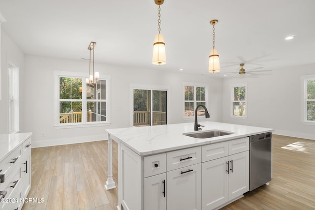 kitchen with sink, stainless steel dishwasher, pendant lighting, a kitchen island with sink, and white cabinets