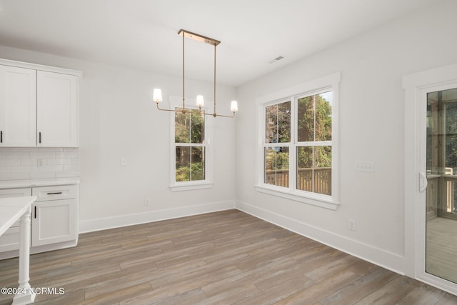 unfurnished dining area featuring a chandelier and light hardwood / wood-style floors