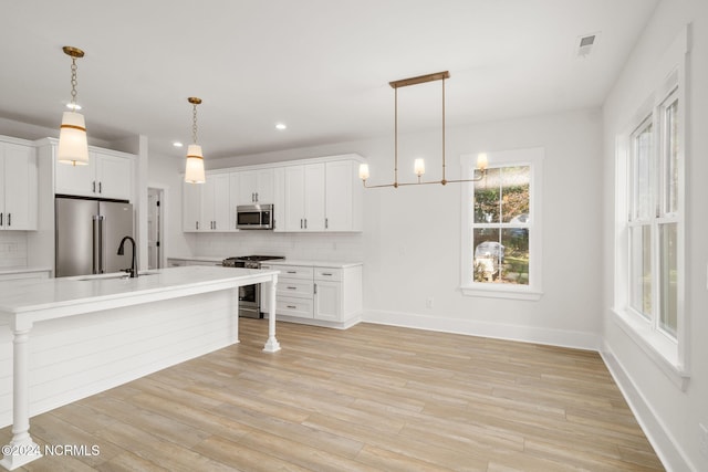 kitchen with backsplash, high quality appliances, white cabinetry, and hanging light fixtures