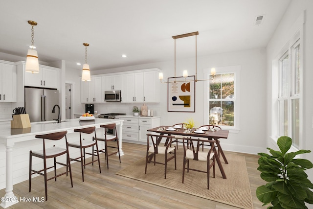 kitchen with pendant lighting, light countertops, high quality appliances, and white cabinets