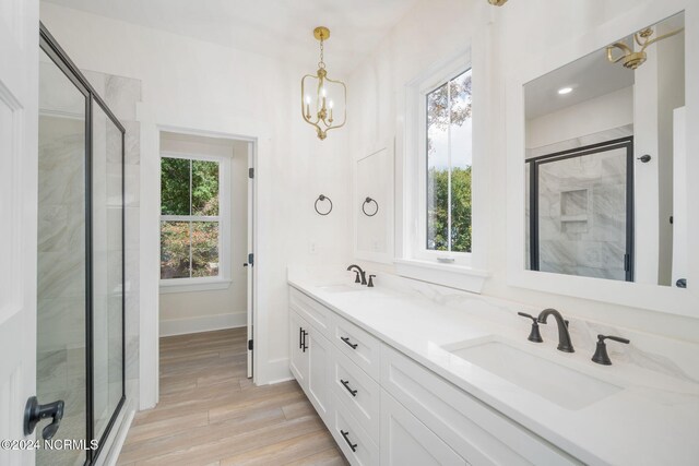 bathroom with hardwood / wood-style flooring, an inviting chandelier, plenty of natural light, and a shower with shower door