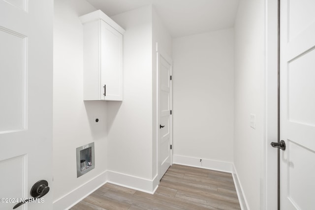 laundry area with hookup for an electric dryer, light hardwood / wood-style floors, and cabinets